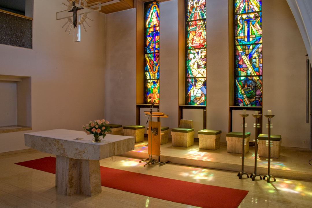 Chorbereich in der Kapelle. Das Abendlicht durchflutet die farbigen Fenster