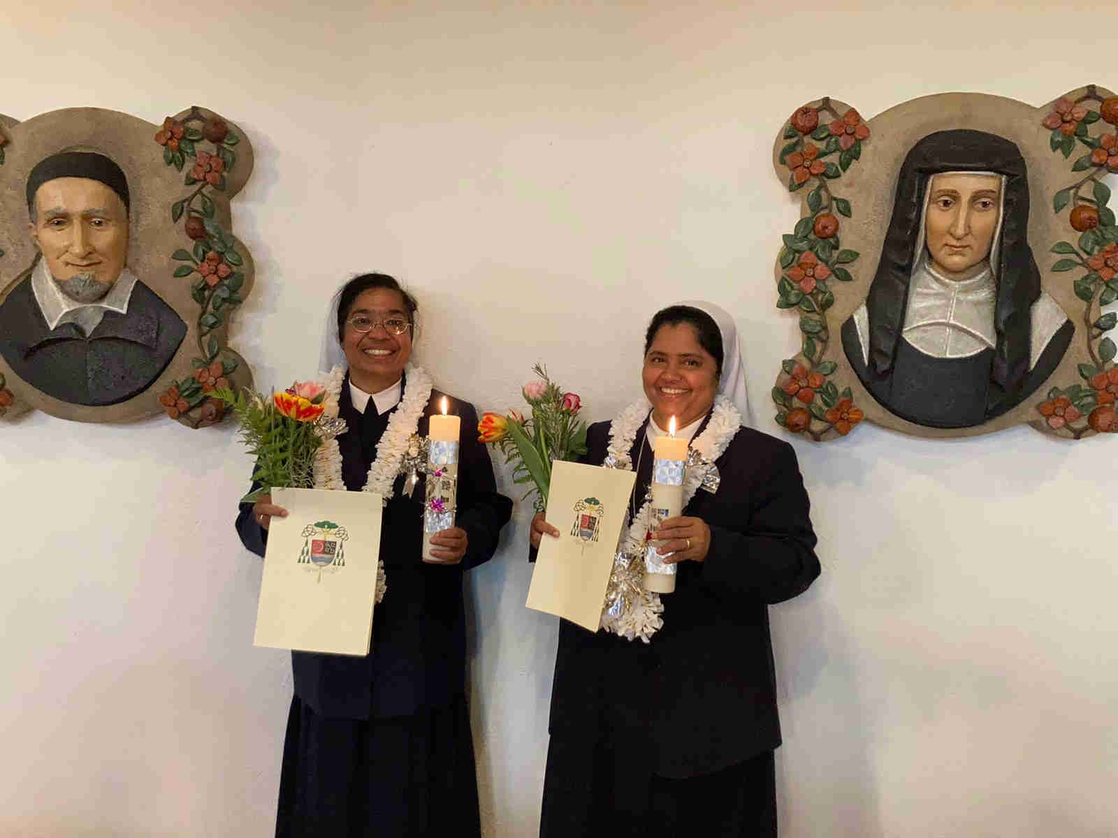 Schwester Elsamma und Schwester Sophy mit Kerzen, Blumen und Urkunde in der Kapelle des Mutterhaus Sankt Vinzenz zum Silbernen Ordensjubiläum. Auf den Seiten befinden sich die Wandilder vom heiligen Vinzenz von Paul und von der heiligen Mutter Luise.